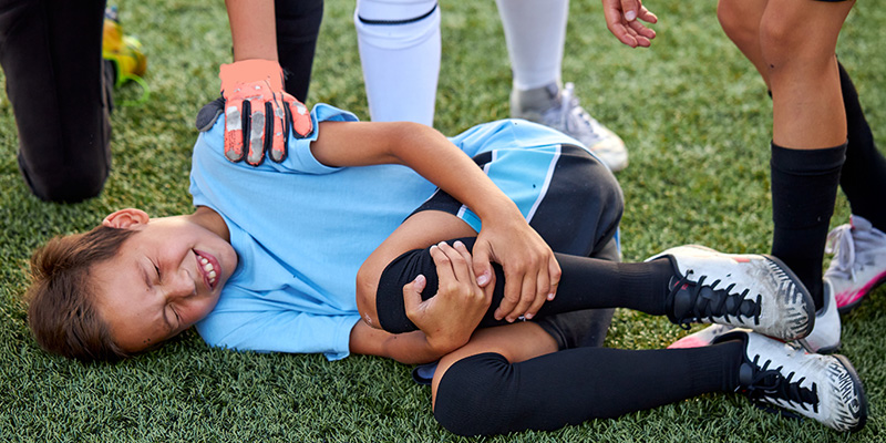 kid laying on ground holding knee