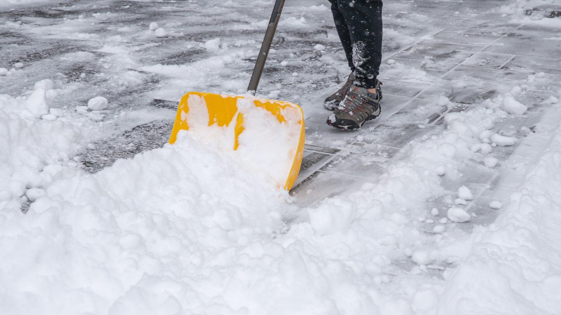 A person practices the best way to shovel a driveway, having made a path down the center first and pushing the snow off to either side.